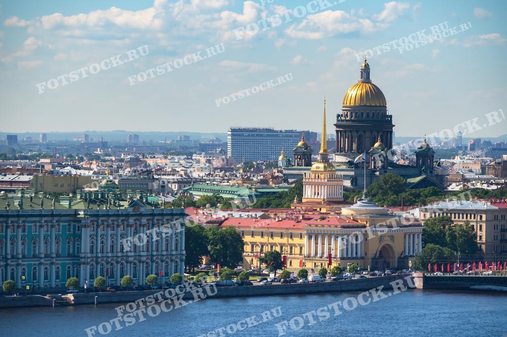 На фотографии изображена панорама центра Санкт-Петербурга, снятая с высоты. В центре кадра виден Зимний дворец и величественный Исаакиевский собор с золотым куполом. На переднем плане река Нева и Адмиралтейство. Летний день придает картине яркость и насыщенность.